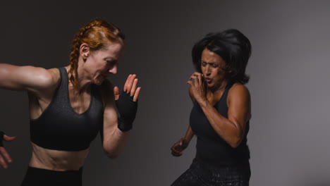 Studio-Shot-Of-Two-Mature-Women-Wearing-Gym-Fitness-Clothing-Doing-Cardio-Exercise-Running-On-The-Spot-Together